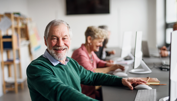 Mehrere Senior/-innen sitzen vor einem PC. | © Halfpoint - Getty Images/iStockphoto